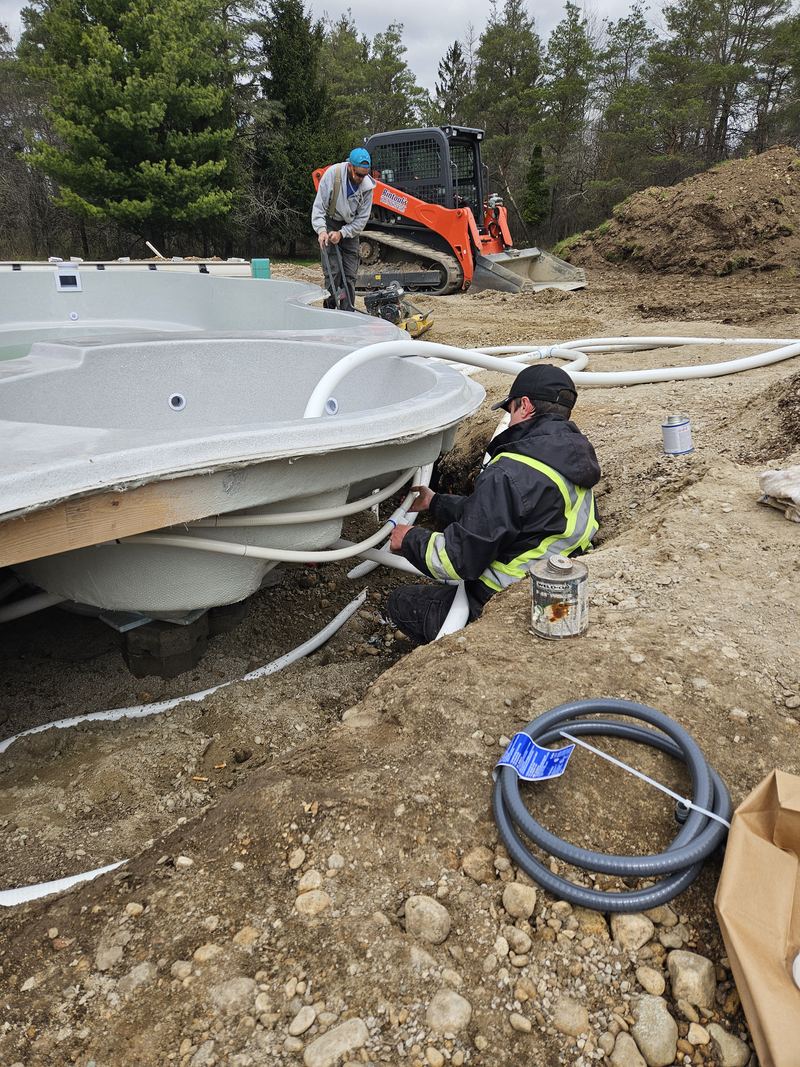 Rintoul's installer in hi-vis gear plumbing a new fibreglass pool shell during installation