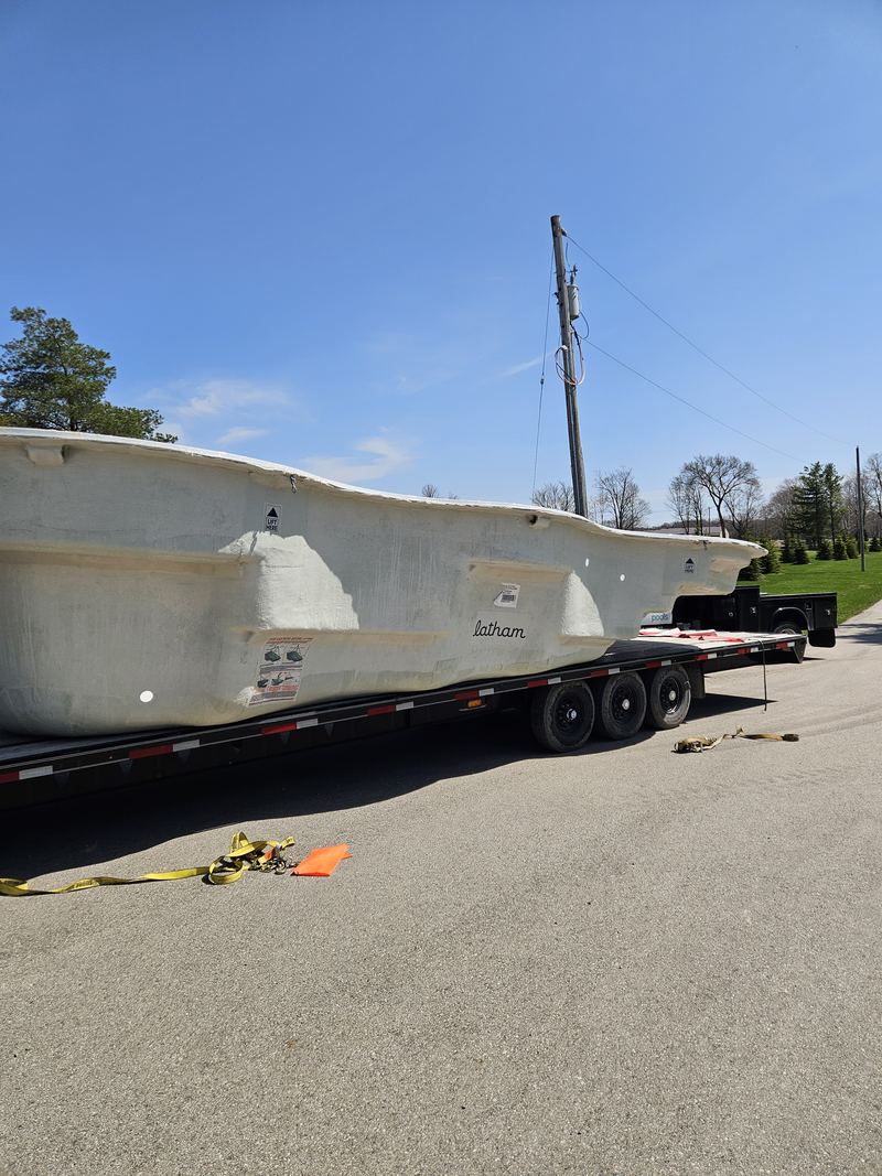 A new fibreglass pool shell arriving on a flatbed trailer