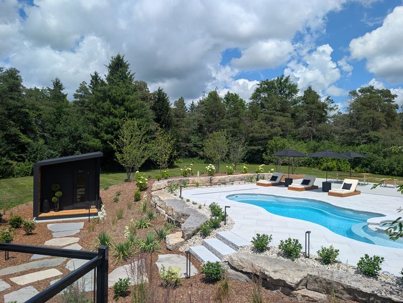 Stone steps leading down to the pool deck past a black cube sauna